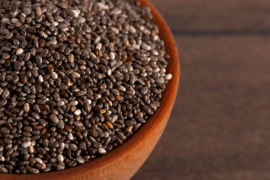 Tahta bir kasedeki organik çiğ Chia tohumları.