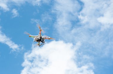Beyaz dron açık mavi gökyüzünde süzülüyor