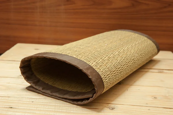 Gerollte Bambusmatten auf Holz-Hintergrund — Stockfoto