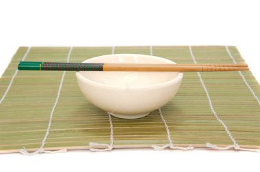 Yemek çubukları ve bambu hasır, izole beyaz arka plan üzerinde kase