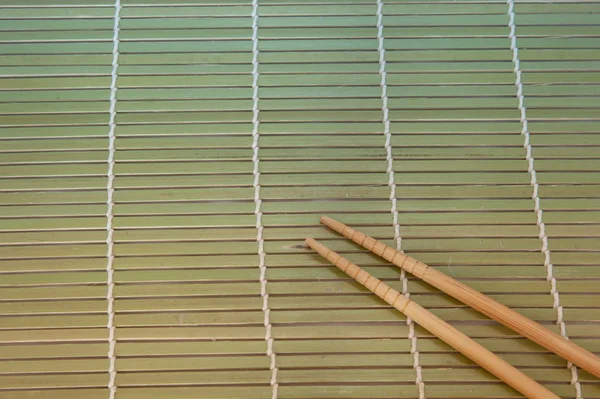 Bacchette e ciotola su tappetino di bambù — Foto Stock