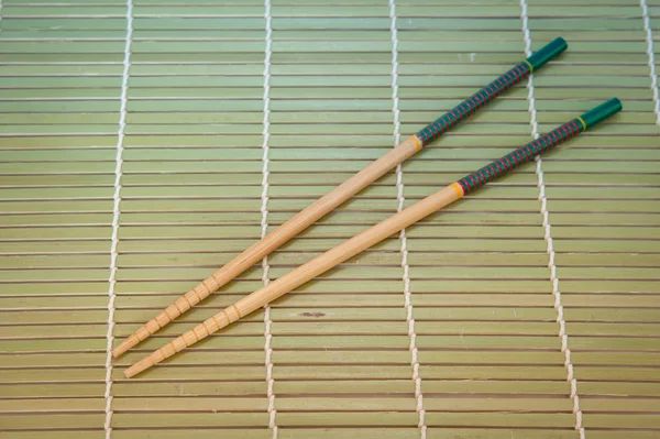 Bacchette e ciotola su tappetino di bambù — Foto Stock