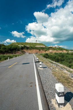 Asfalt Yolu: Kayalarla kaplı manzara, bulutlarla güneşli gökyüzü ve yaz akşamları güzel asfalt yollar. Dağlarda otoyol. Tayland.