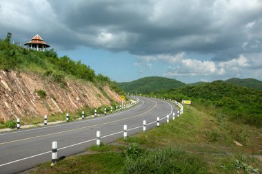 Asfalt Yolu: Kayalarla kaplı manzara, bulutlarla güneşli gökyüzü ve yaz akşamları güzel asfalt yollar. Dağlarda otoyol. Tayland.
