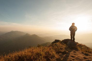 bir dağın tepesinde duran ve gündoğumu zevk sırt çantası ile fiyatı