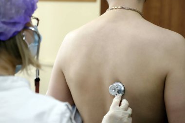 Bir doktor, bir koronavirüs hastasının akciğerlerini fonoendoskopla dinler.