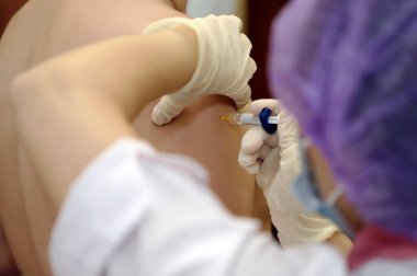 Doktor, insanın omzuna koronavirüs aşısı yerleştirdi.