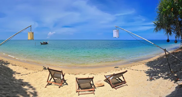 Tropical beautiful beach with crystal clear water and boat on the island of Koh Lanta (Thailand). Loungers to relax on the beach.