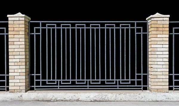 Металлический забор с кирпичными колоннами — стоковое фото