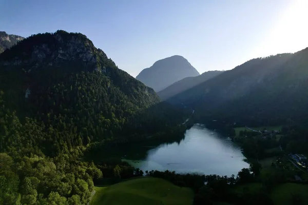 Alp Gölü Thumsee 'nin 4K Hava Aracı videosu. Turkuaz su ve yemyeşil ormanlarla çevrili. Gün batımında yüksek dağlar, Bad Reichenhall Almanya' da altın saat.