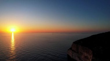 Dingli Kayalıkları 'ndaki Malta' nın en yüksek noktasının insansız hava aracı görüntüsü, gün batımında denize dik bir şekilde düşen yemyeşil çimenler ve kaya oluşumları, altın saat. Güneş altın parıltısını kayalara ve Dingli Radar 'a veriyor.