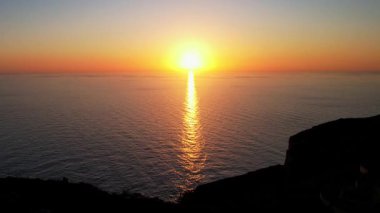 Dingli Kayalıkları 'ndaki Malta' nın en yüksek noktasının insansız hava aracı görüntüsü, gün batımında denize dik bir şekilde düşen yemyeşil çimenler ve kaya oluşumları, altın saat. Güneş altın parıltısını kayalara ve Dingli Radar 'a veriyor.