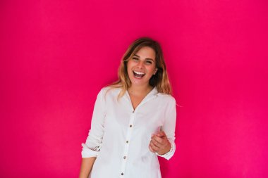 Pembe arka planda genç bir kız, kameraya gülümsüyor..