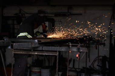 Atölyesindeki lambayı kullanarak koruyucu eldiven takan isimsiz bir işçinin resmi..