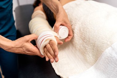 Fizyoterapi kliniğinde tanınmayan bir işçi hastaların ellerini bandajla sarıyor..