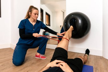 Profesyonel fizyoterapist bir kadından yardım alan bir adamın stok fotoğrafı..