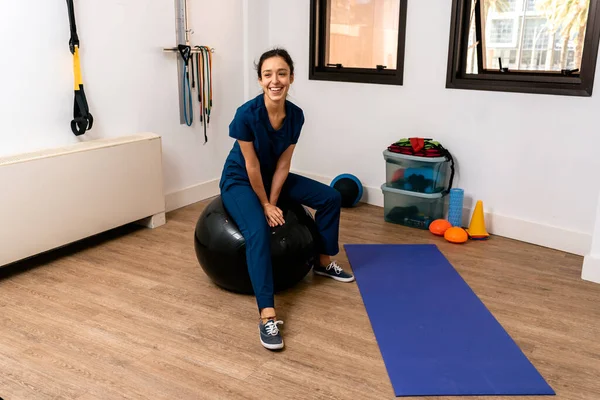 Woman sitting on a pilates ball in physiotherapy clinic.