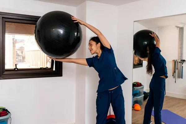 Woman holding a pilates ball in physiotherapy clinic.