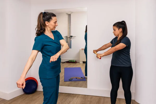 Profesyonel bir işçiyle rehabilitasyon egzersizleri yapan bir kadının stok fotoğrafı..
