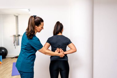 Tanımlanamayan bir kadının profesyonel işçilerle rehabilitasyon egzersizleri yaparken çekilmiş resmi..