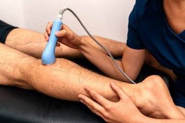 Tanınmayan fizyoterapistin, sedyede yatan hastaya ultrasonik tedavi uygularken çekilmiş fotoğrafı..