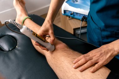 Tanınmayan fizyoterapistin paspasda yatan hastaya ultrasonik tedavi uygularken çekilmiş fotoğrafı..