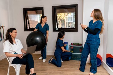 Fizyoterapi kliniğinde çalışan mutlu kadınlardan oluşan birleşik çalışma ekibinin resmi..