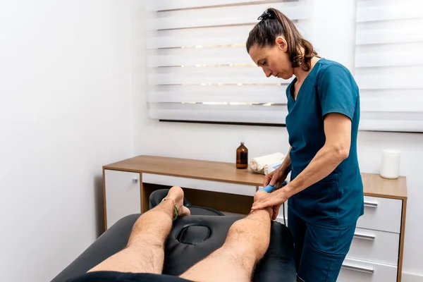 Stock photo of physiotherapist giving ultrasonic treatment to patient lying in stretcher.