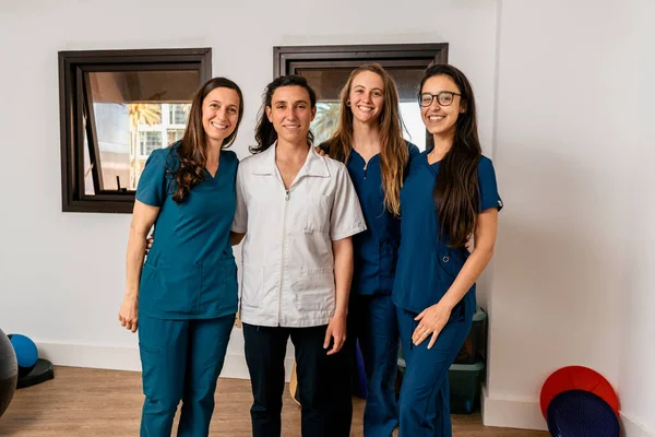 Fizyoterapi kliniğinde çalışan mutlu kadınlardan oluşan birleşik çalışma ekibinin resmi..