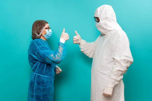 Stock photo of unrecognized person talking with healthcare worker wearing protective suit for covid19.