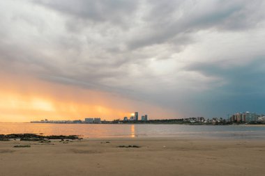Sahilde güzel bir gün batımı. Arkasında şehrin ufuk çizgisi var..