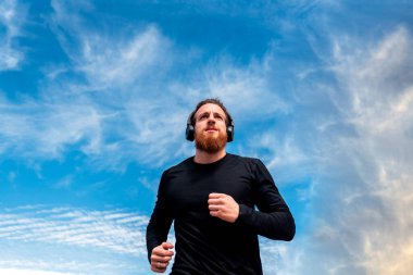 Müzik dinlerken dışarı koşan odaklanmış sakallı bir adam..