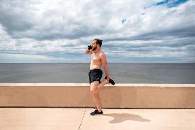 Egzersiz yaptıktan sonra dışarı çıkıp telefonunu kullanan mutlu bir adam..