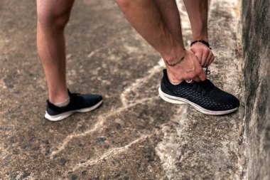 Sokakta ayakkabılarını bağlayan yüzsüz koşucu..