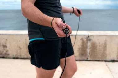 Unrecognized bearded man using jumping rope outdoors.