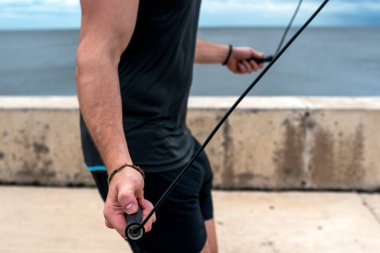 Unrecognized bearded man using jumping rope outdoors and looking at front.
