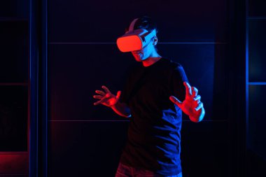 Sanal gerçeklik gözlüğü kullanan oyuncu evde havalı ışıklarla eğleniyor..