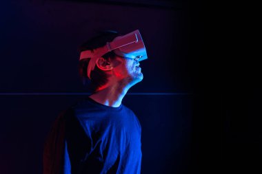 Sanal gerçeklik gözlüğü kullanan oyuncu evde havalı ışıklarla eğleniyor..