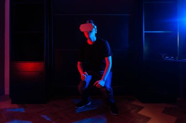 Sanal gerçeklik gözlüğü kullanan oyuncu evde havalı ışıklarla eğleniyor..