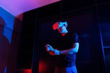 Sanal gerçeklik gözlüğü kullanan oyuncu evde havalı ışıklarla eğleniyor..