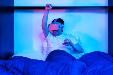 Oyuncu çocuk sanal gerçeklik gözlüğü kullanıyor. Yatağında eğleniyor..