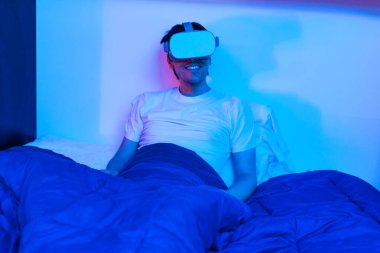 Oyuncu çocuk sanal gerçeklik gözlüğü kullanıyor. Yatağında eğleniyor..