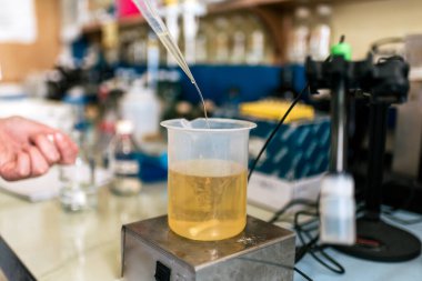 Laboratuvarında test tüplerini dolduran tanınmayan bilim adamının stok fotoğrafı..