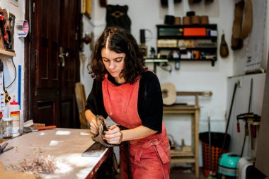 Kadın Luthier müzik aleti atölyesinde gitar çalıyor.
