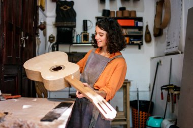 Kadın Luthier müzik aleti atölyesinde gitar çalıyor.