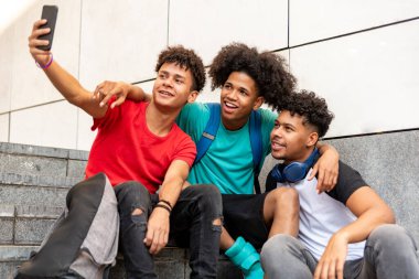 Çok ırklı arkadaşlar sokakta cep telefonlarıyla selfie çekiyorlar.