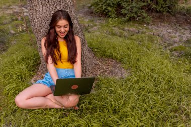 Parkta bilgisayarı olan beyaz bir kadın.