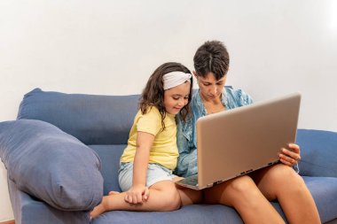 Anne ve kızı kanepede bilgisayarı kullanıyor..