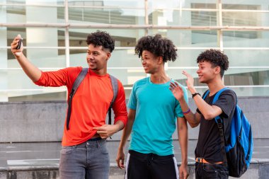 Bir grup afro Latin erkek arkadaş şehirde cep telefonuyla selfie çekip eğleniyorlar..