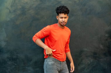 Duvara dayanmış genç Latin adamın portresi.